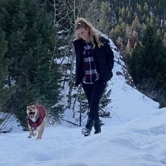 Dr. Melissa Burns walking a snowy mountain trail in Colorado with her dog.