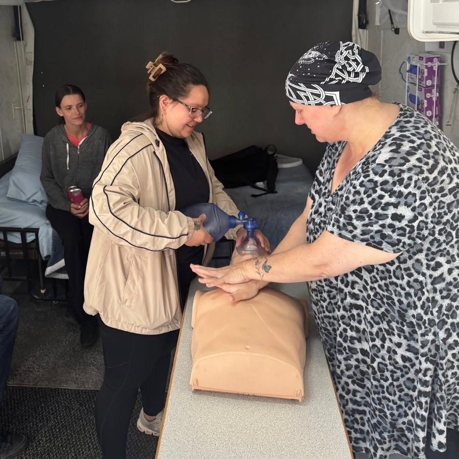 A student and an instructor practicing bag-valve-mask ventilation on an adult manikin inside the mobile skills lab.